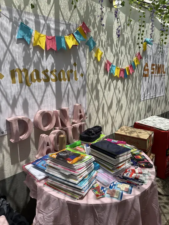 Mesa de la colecta con el letrero «Dona aquí», cuadernos, colores, plumas y otros útiles escolares.