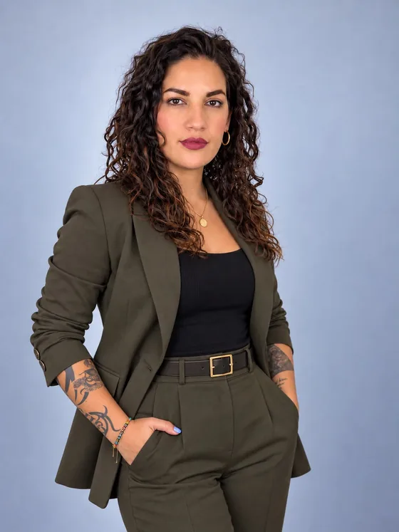 Retrato de Rebeca Kuri con traje verde olivo sobre fondo azul.
